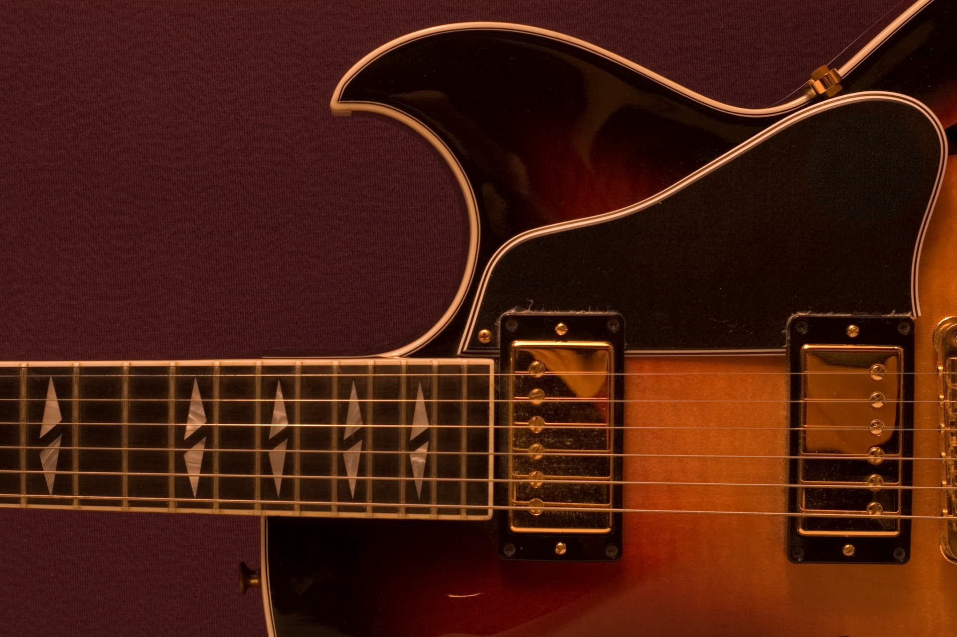 Guitarra archtop sunburst, detalhe da escala, captadores dourados e encordoamento.